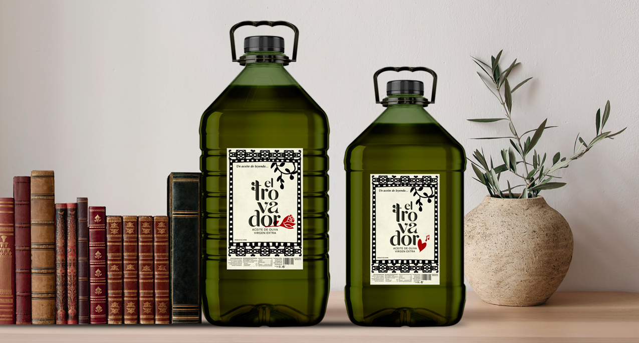 Botellas de 5 litros de aceite El Trovador junto a libros antiguos y rama de olivo